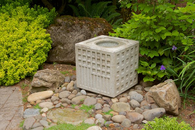 Different textures, shapes and colors in hardscape, plants and statuary in a tranquil shady retreat